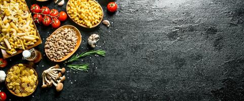 Different types of raw paste in bowls with mushrooms, rosemary and tomatoes. photo