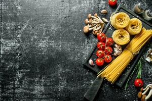 Raw tagliatelle and spaghetti with mushrooms, tomatoes and spices. photo