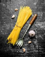 Raw spaghetti with garlic and a ladle. photo