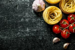 Raw tagliatelle paste with garlic and tomatoes. photo