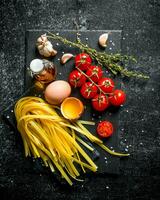 Home made raw pasta with thyme, eggs, oil and tomatoes. photo