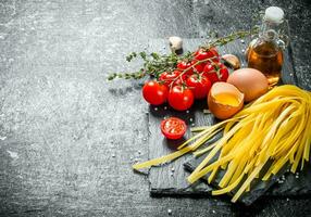 Home made raw pasta with thyme, eggs, oil and tomatoes. photo