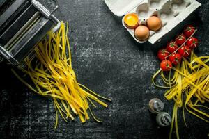 Home made raw pasta with tomatoes on a branch, eggs and spices. photo