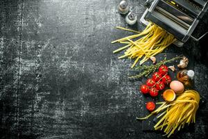 Machine for making homemade pasta and raw pasta with tomatoes and oil. photo