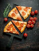 Slices of pepperoni pizza with tomatoes and rosemary. photo