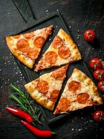 Slices of pepperoni pizza with chili, rosemary and cherry tomatoes. photo