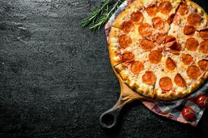 Sliced pepperoni pizza with rosemary and tomatoes. photo