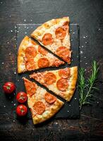 Slices of pepperoni pizza with rosemary and tomatoes. photo