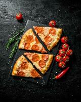 Slices of pepperoni pizza with tomatoes and rosemary. photo