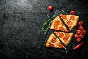 Slices of pepperoni pizza with tomatoes and rosemary. photo