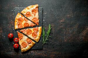 Slices of pepperoni pizza with rosemary and tomatoes. photo