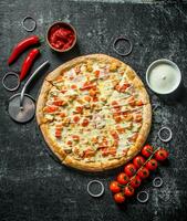 Sliced pizza with cherry tomatoes, onion rings and cheese sauce in bowl. photo