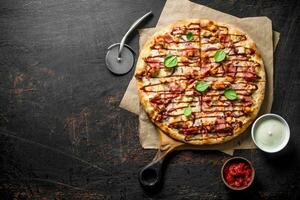 Barbecue pizza with cheese and tomato sauces in bowls. photo