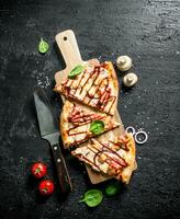 Pieces of barbecue pizza on a wooden cutting Board. photo