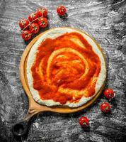 Preparation pizza. Dough on a cutting Board with cherry tomatoes. photo