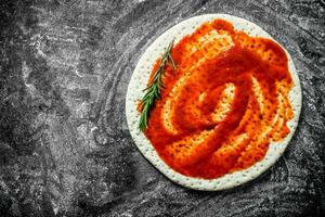 Raw pizza. Pizza dough with tomato paste. photo