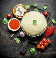 Raw pizza. Dough with various ingredients for cooking homemade pizza. photo