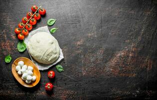 Pizza dough with mozzarella and cherry tomatoes. photo