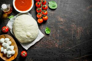 Raw pizza. Dough with different ingredients for pizza. photo