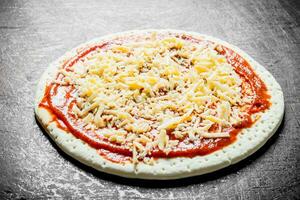 Preparation pizza. Rolled out round dough with tomato paste and cheese. photo