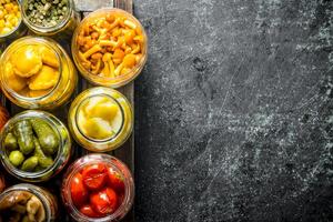 Jars with variations of pickled food on a tray. photo