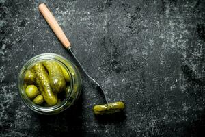 Open glass jar with pickled cucumbers. photo