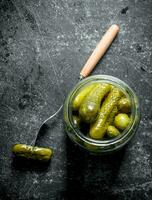 Open glass jar with pickled cucumbers. photo