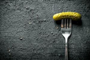 One pickled cucumber on a fork. photo