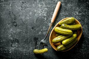 Preserved cucumbers on a plate with one cucumber on a fork. photo