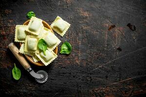 Raw Ravioli in a bowl with the spinach leaves. photo