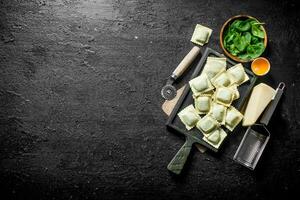 crudo Ravioles con hierbas y parmesano queso en un corte tablero. foto