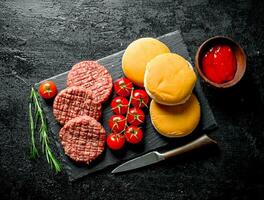 Raw burgers with cherry tomatoes, bread and rosemary. photo