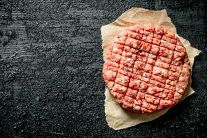 One Raw burger on paper. photo