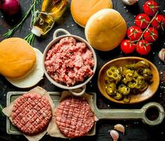 Raw burgers with ground beef, oil, buns and tomatoes. photo