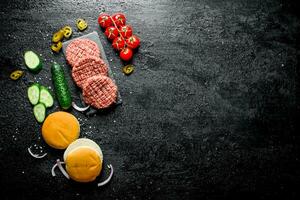 Raw burgers. Preparation of burgers from beef patties, tomatoes and cucumbers. photo