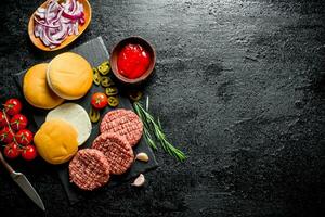 Raw burgers with tomatoes, scones, sauce and chopped onion. photo