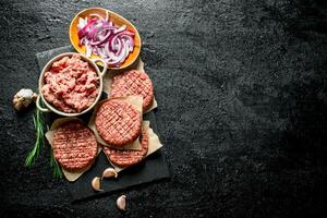 Raw burgers with ground beef and sliced onions in bowls. photo