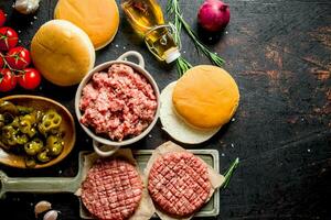 Raw burgers with ground beef, oil, buns and tomatoes. photo