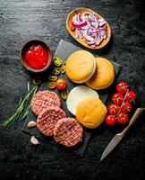 Raw burgers with tomatoes, scones, sauce and chopped onion. photo