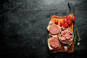 Raw burgers and ground beef with tomatoes, garlic cloves and thyme. photo