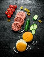 Raw burgers. Preparation of burgers from beef patties, tomatoes and cucumbers. photo