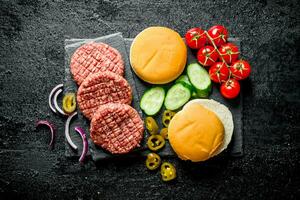 Raw burgers. Preparation of burgers from beef patties, tomatoes and cucumbers. photo