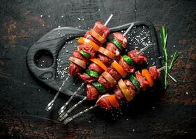 Raw beef kebab with vegetables and herbs on a cutting Board. photo