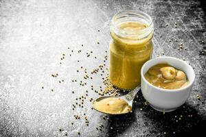 Mustard in a glass jar, spoon and bowl. photo