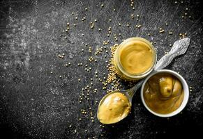 Mustard in a glass jar, spoon and bowl. photo