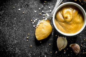 Mustard in a bowl with garlic cloves. photo