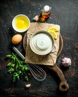 Mayonnaise on a cutting Board with greens, eggs and oil. photo