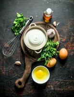 Mayonnaise on a cutting Board with parsley, eggs and garlic. photo