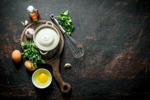 Mayonnaise on a cutting Board with parsley, eggs and garlic. photo