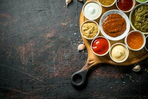 Different types of sauces on the cutting Board with garlic cloves. photo